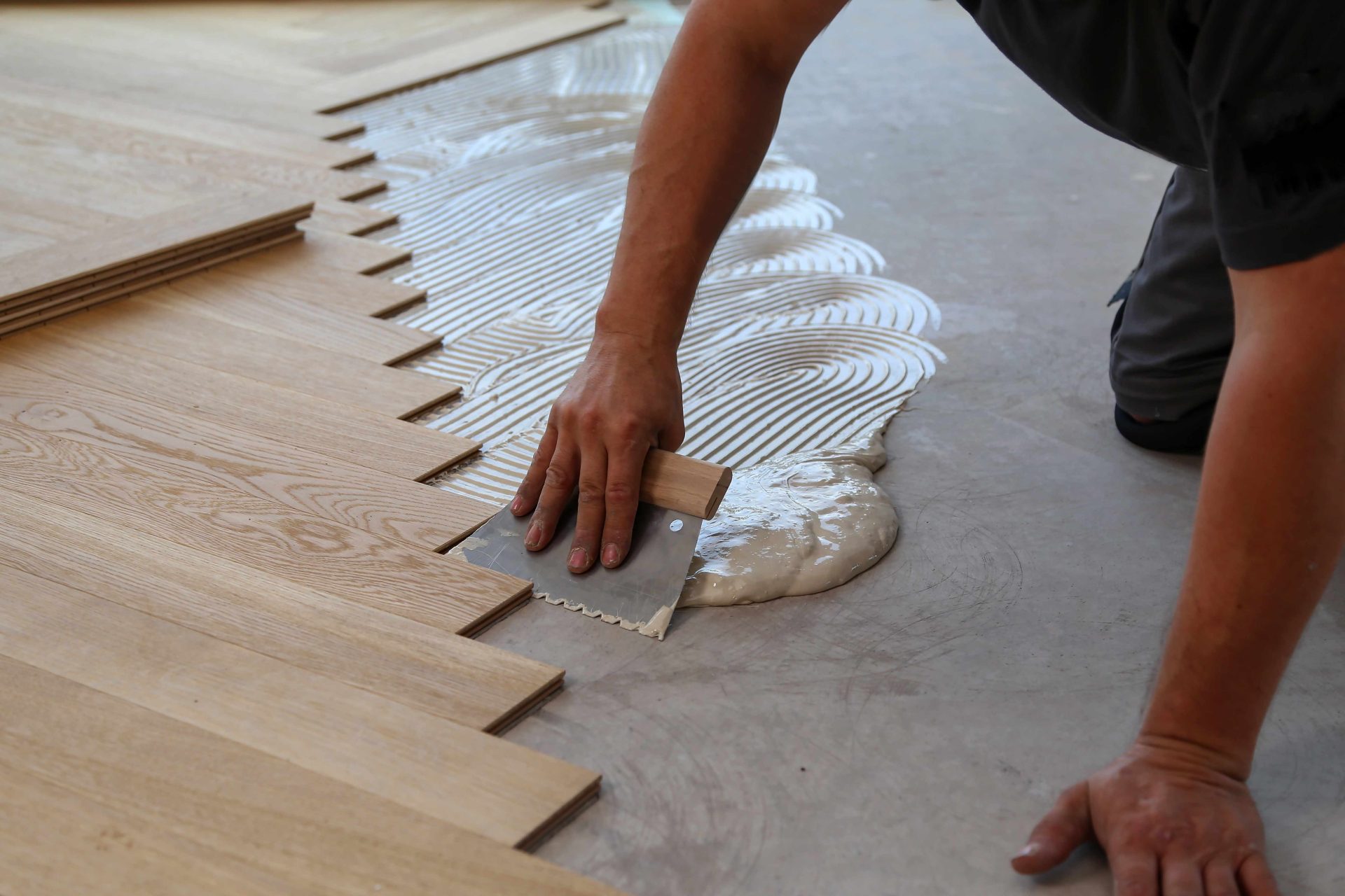 Ouvrier posant un parquet en bois sur une surface au sol